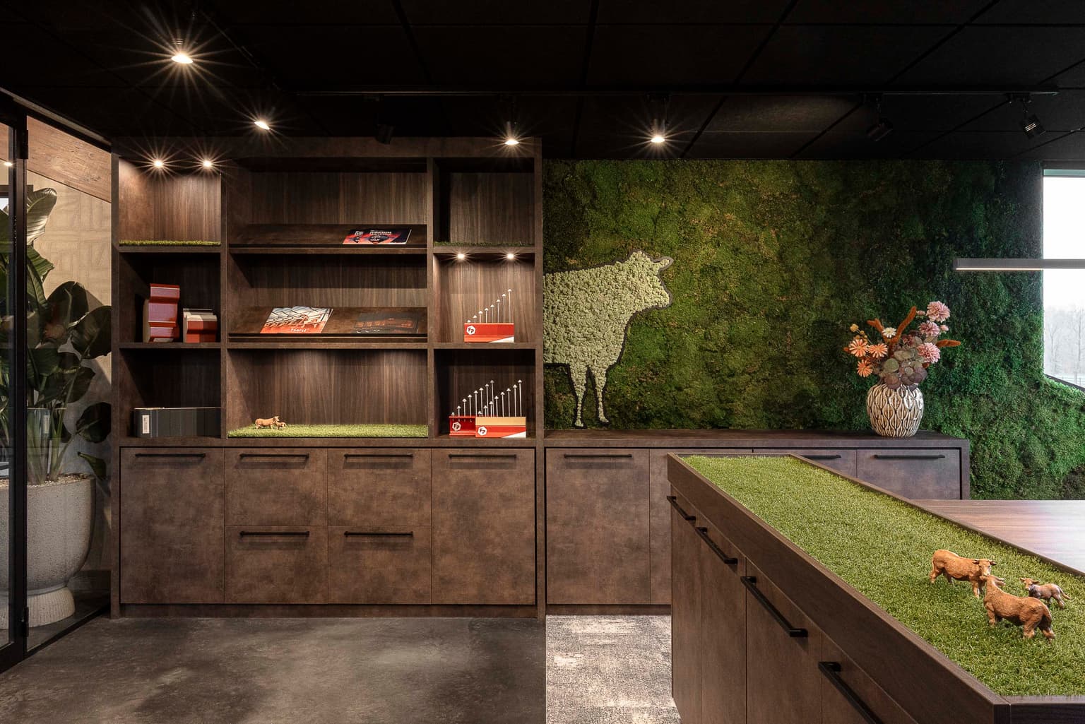 Pantry met donkerbruine kast, groene moswand en koeien silhouet. 
