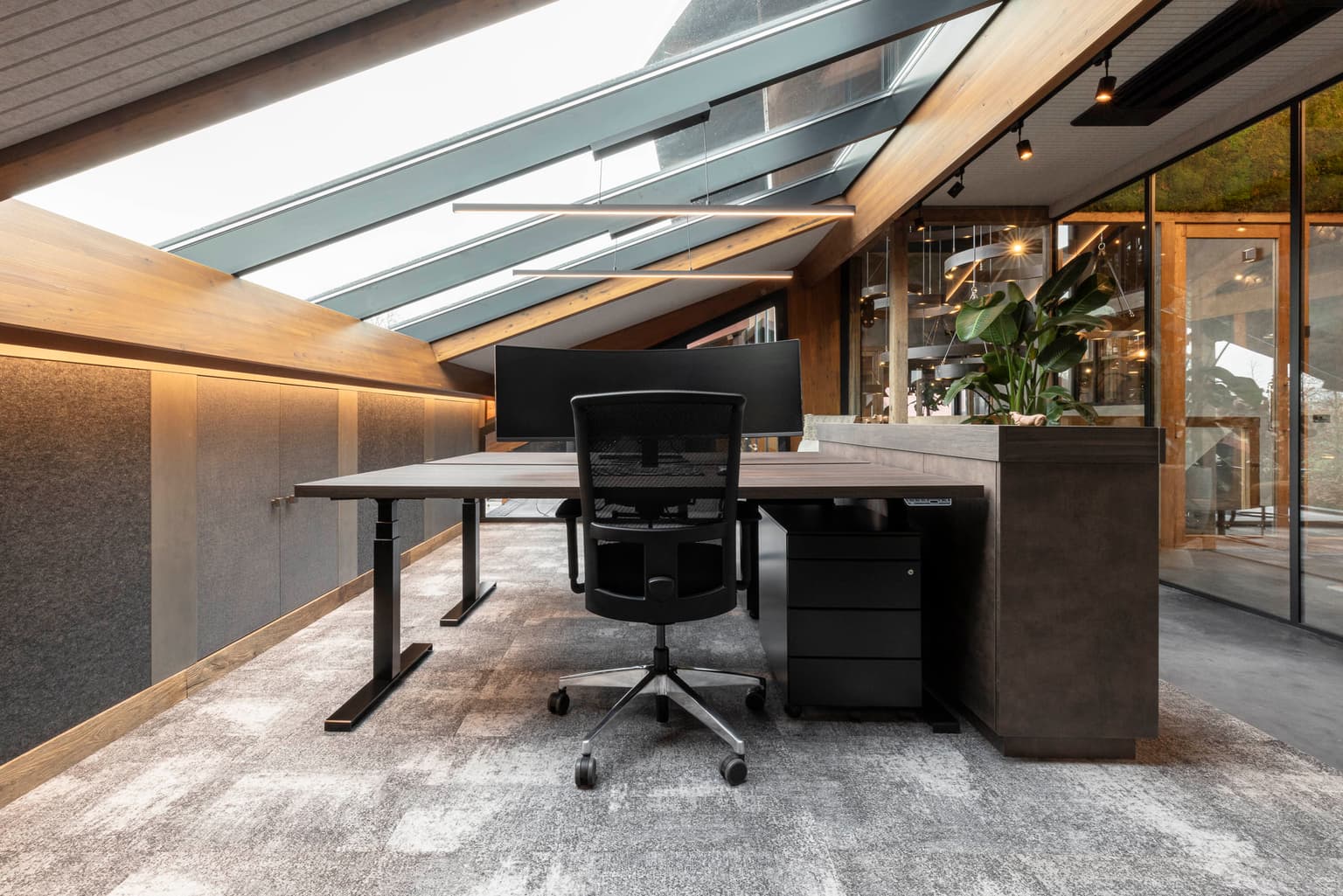 Werkplek met donkerbruin bureau en zwarte bureaustoel. 
