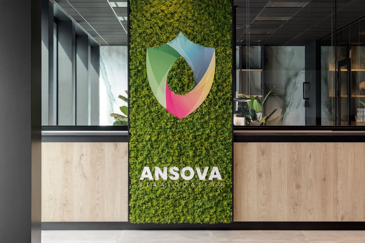 Entree bij Ansova met een moswand en daarop hun logo. 