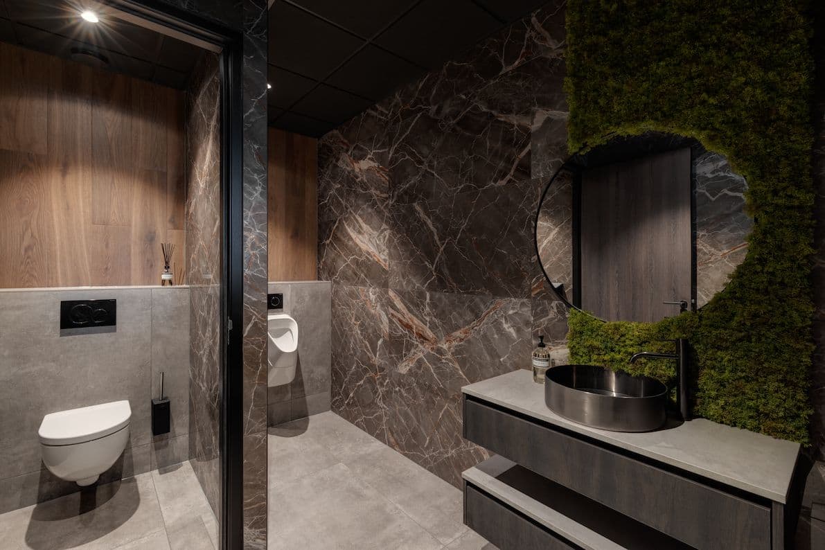 Toiletruimte met daarin grijs steen en rechts een grijze, marmeren wand met bruine aders.