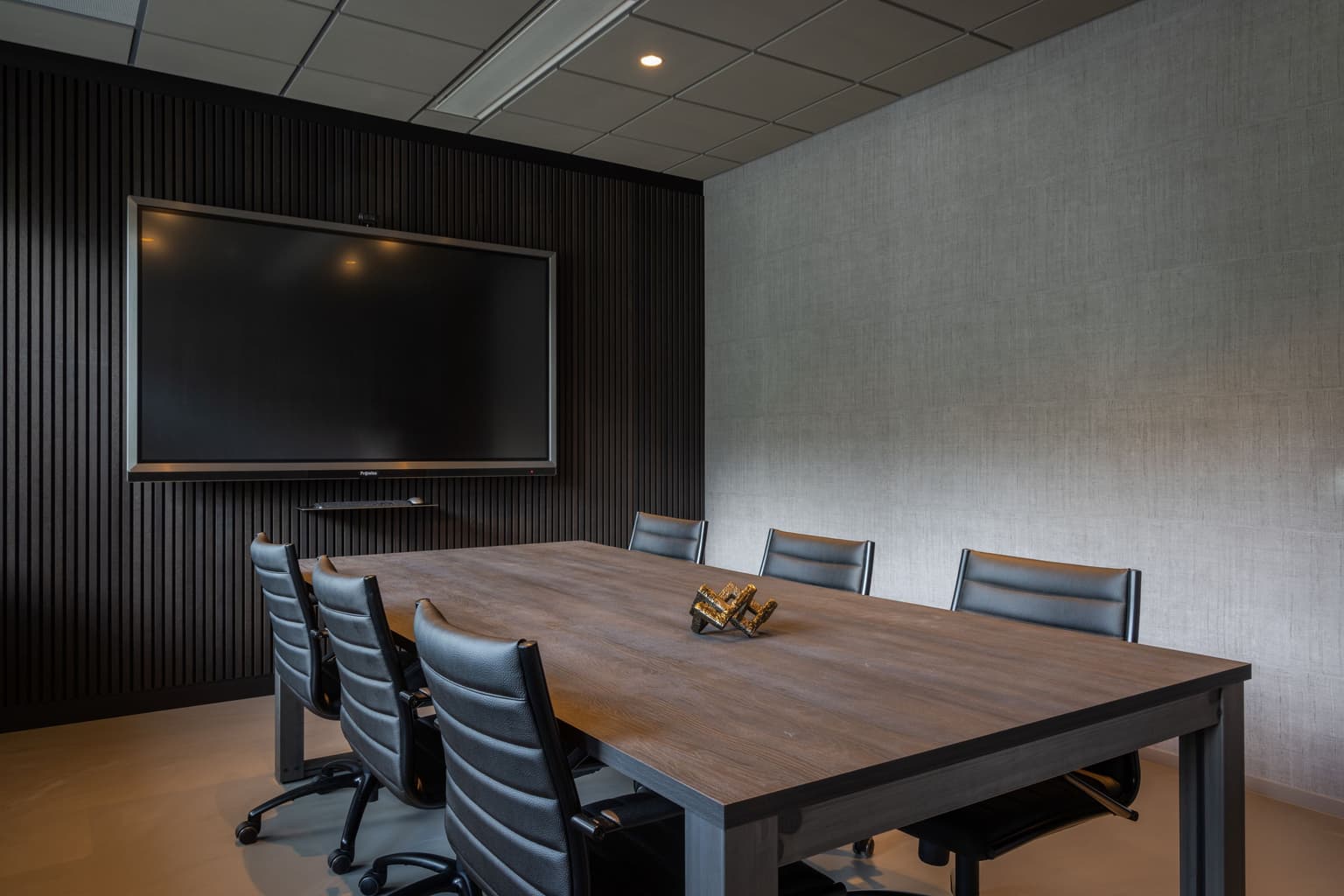 Vergaderruimte met blankstalen vergadertafel en leren vergaderstoelen eromheen. 