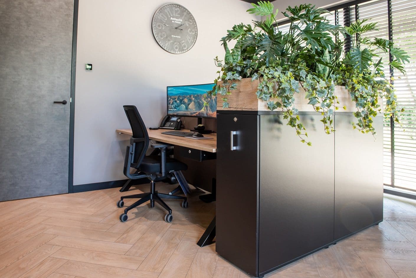 Duobureau geflankeerd door schuifdeurkast met plantenbak erop. 