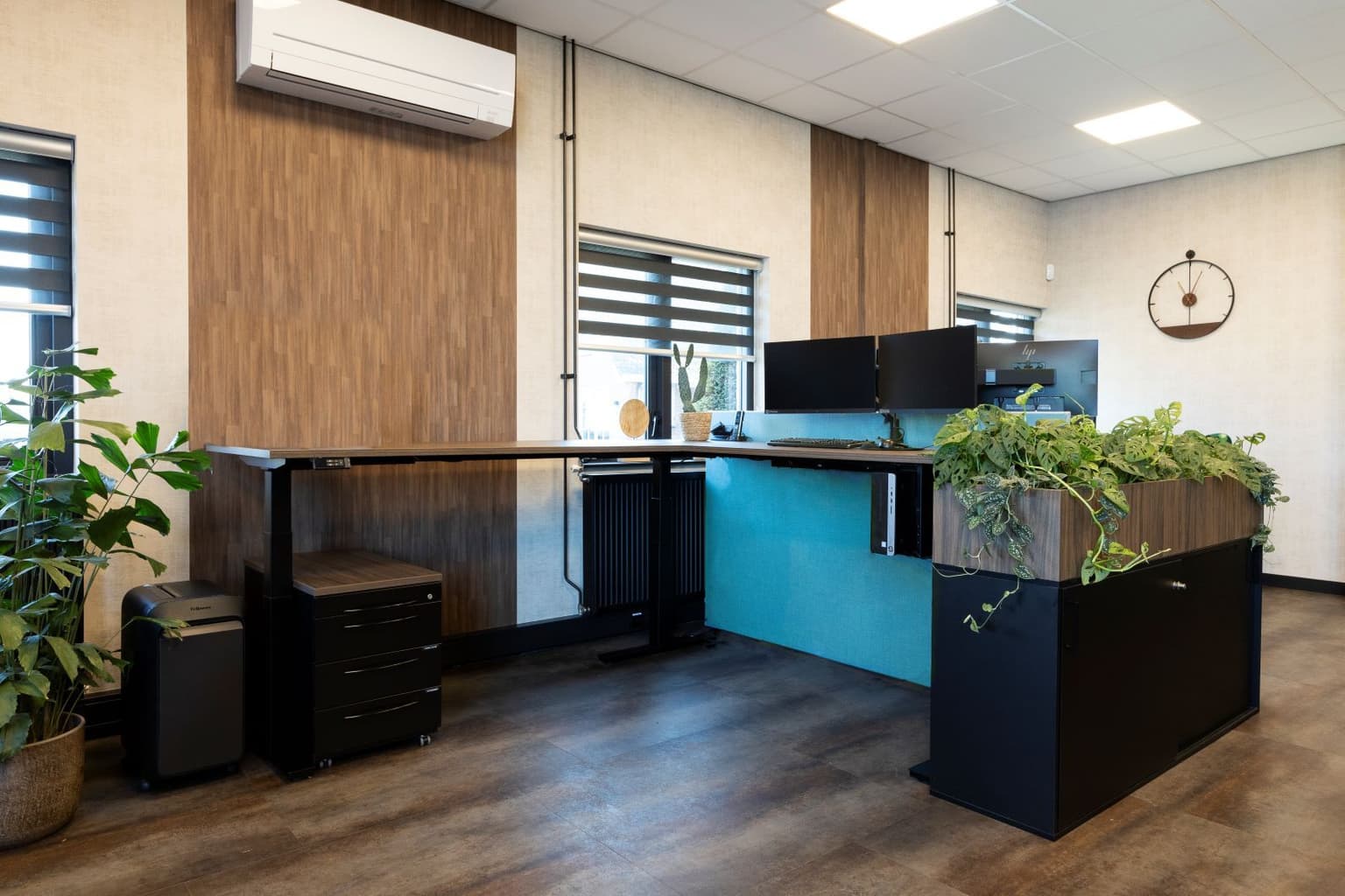 Zit sta hoekbureau met een blauw akoestisch paneel. 