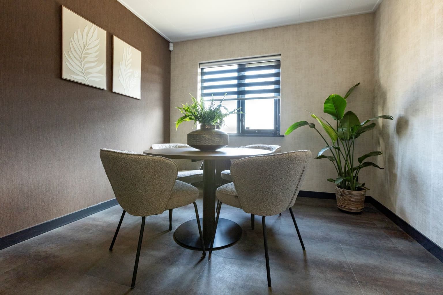 Vergaderruimte met ronde tafel en lichte vergaderstoelen. 