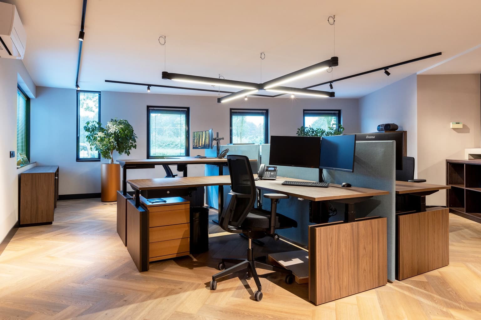 Eiland van drie werkplekken waaronder verstelbare hoekbureaus.