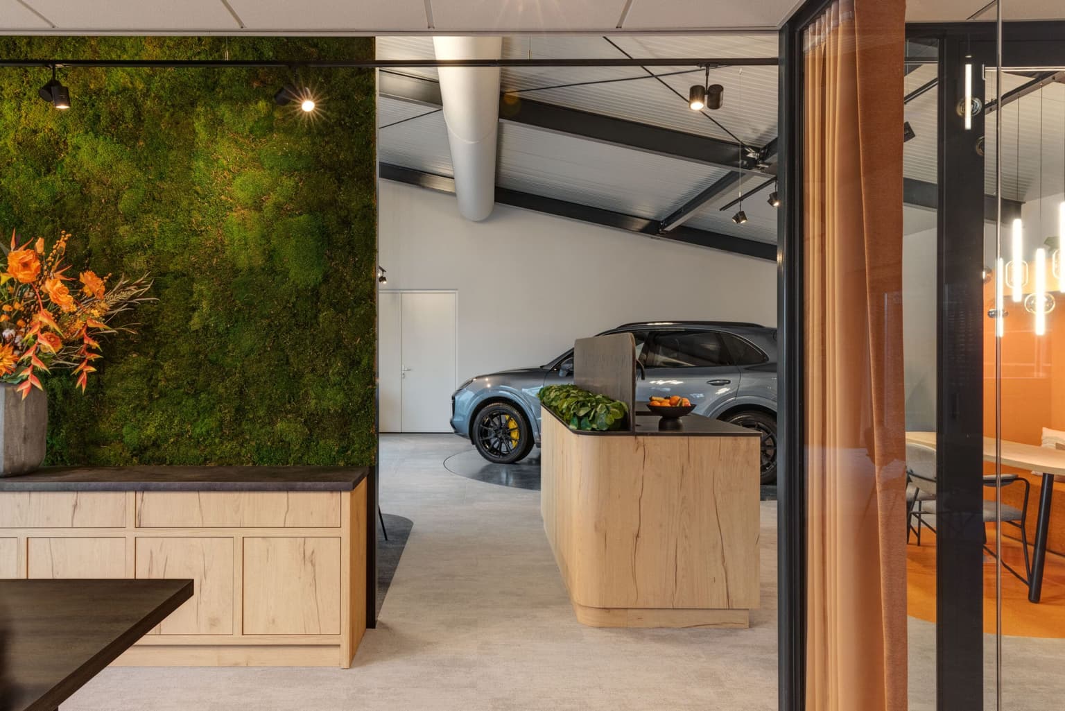 Showroom met een moswand en oranje bloemen erin.