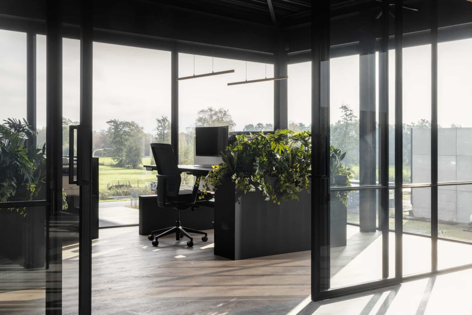 Kantoorinrichting van De Rietdekker, met een hoekje waar een plantenbak met kunstplanten en een duobureau staat.